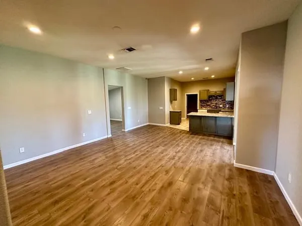 a view of an empty room and kitchen with kitchen area