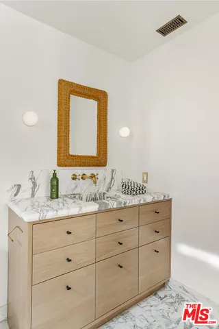a bathroom with a granite countertop sink vanity and mirror