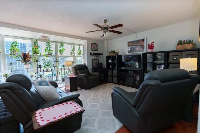 a living room with furniture ceiling fan and a floor to ceiling window