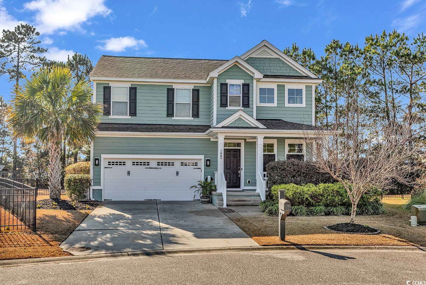 View of front of property with a garage, driveway, a shingled roof, and a porch