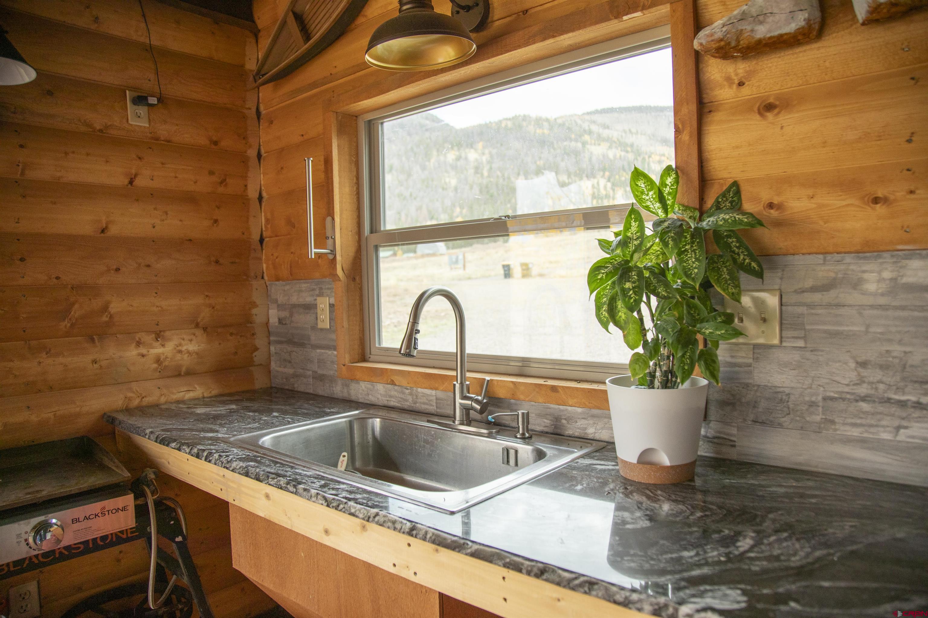258 Diamond Road Creede, CO 81130 - Photo 21 of 30 a sink with a granite counter top a potted plant and a window
