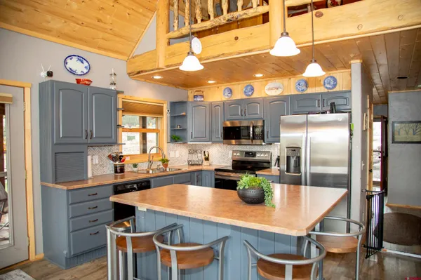 a kitchen with stainless steel appliances kitchen island granite countertop a refrigerator a stove and a dining table with wooden floor
