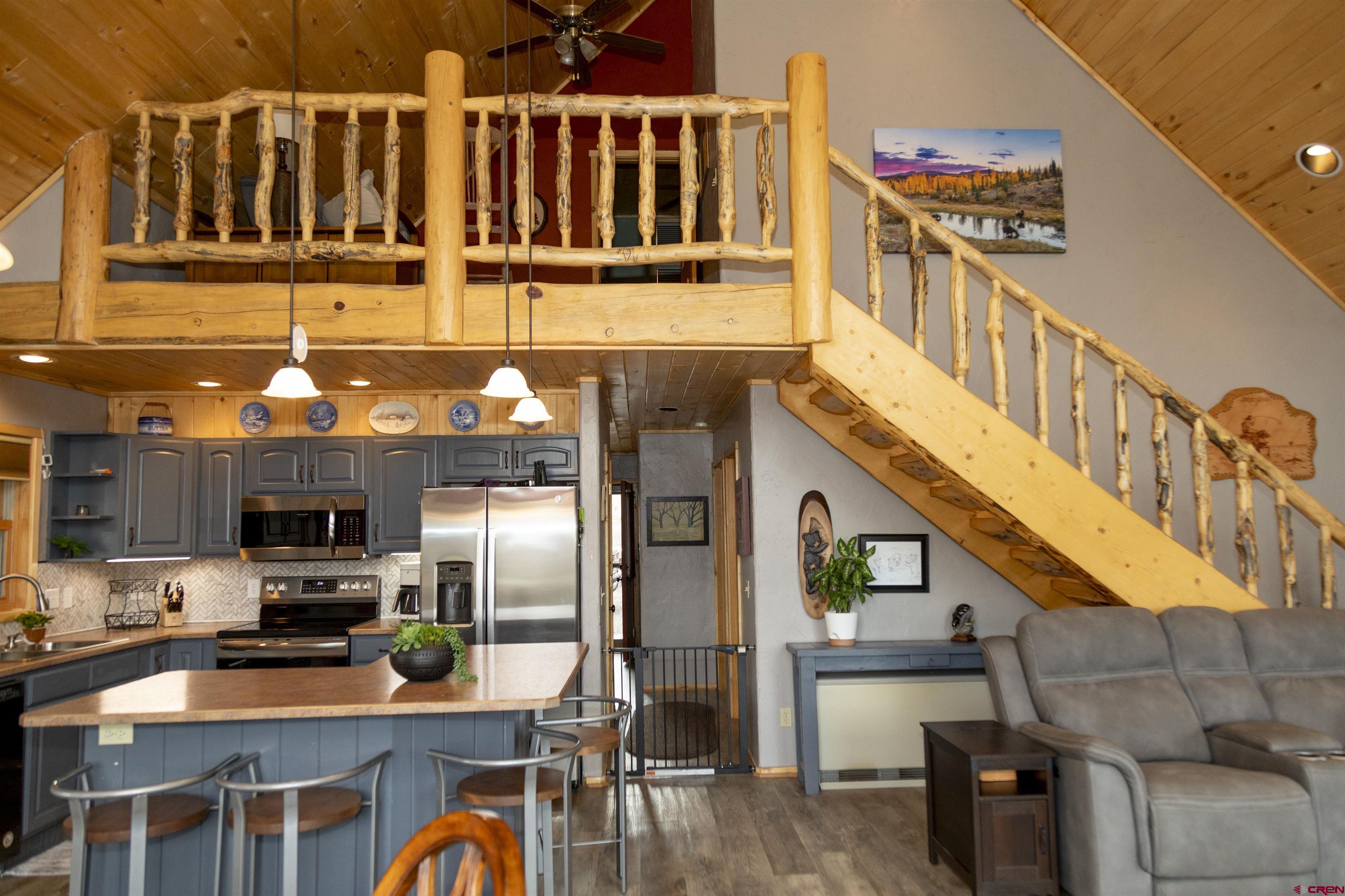 258 Diamond Road Creede, CO 81130 - Photo 5 of 30 a kitchen with stainless steel appliances kitchen island granite countertop a refrigerator a stove and a dining table with wooden floor