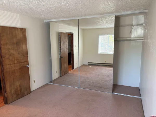 a view of an empty room with closet and a window