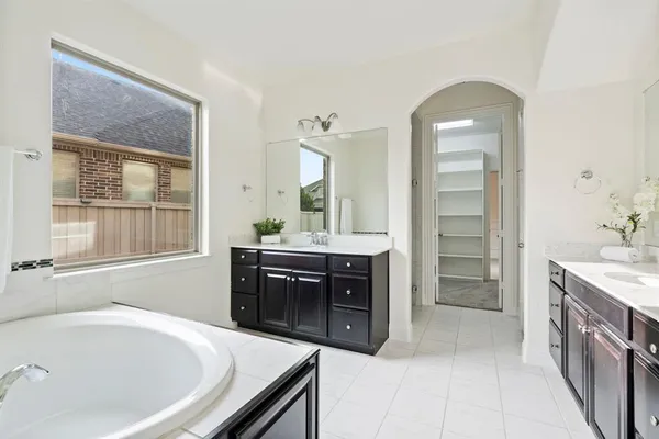 a spacious bathroom with a tub sink and mirror