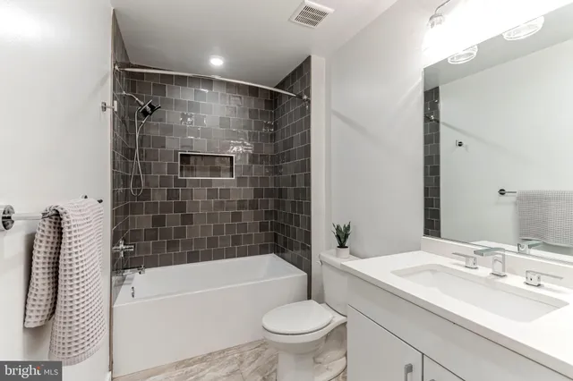a bathroom with a bathtub shower sink vanity mirror and toilet