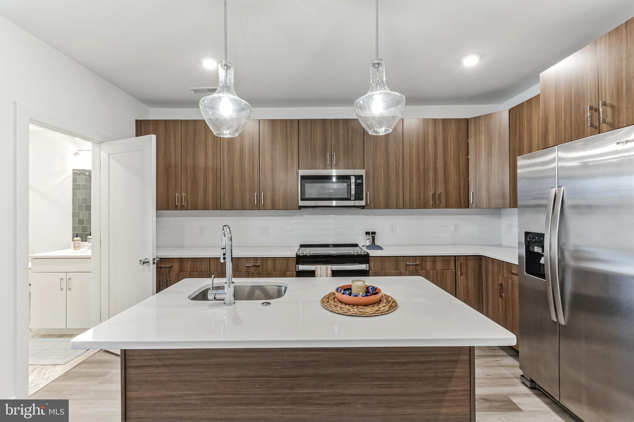 5801 Ridge Avenue, Unit 201 Philadelphia, PA 19128 - Photo 3 of 26 a kitchen with a kitchen island a sink stainless steel appliances and cabinets