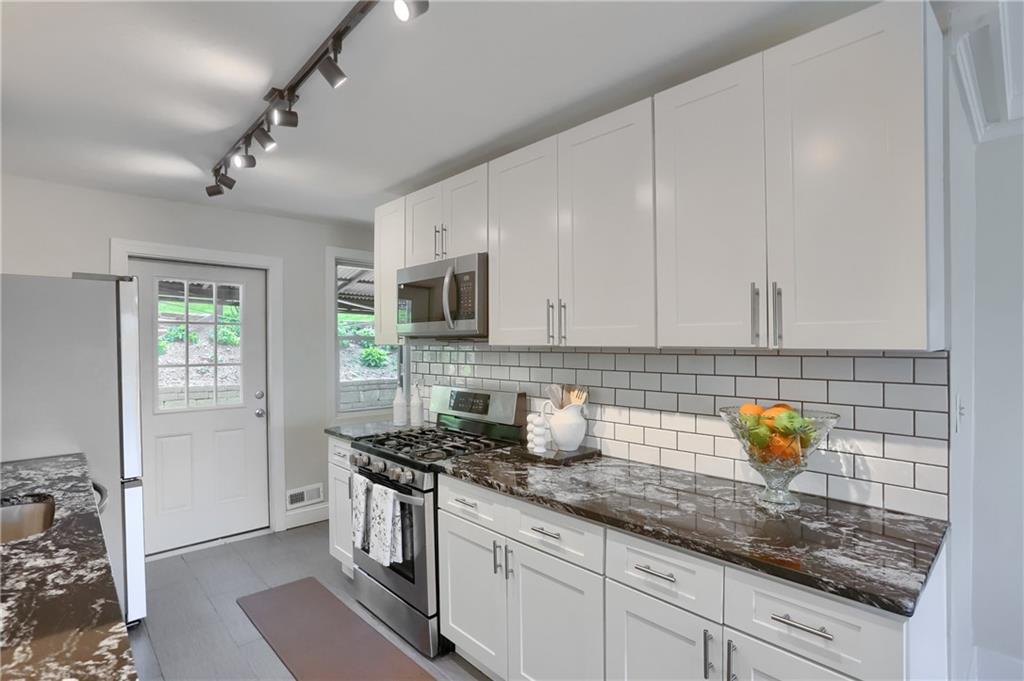 5216 Verona Road Verona, PA 15147 - Photo 19 of 42 a kitchen with stainless steel appliances granite countertop a refrigerator a stove a sink and white cabinets with wooden floor