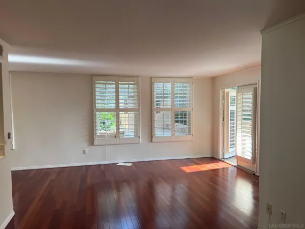 an empty room with wooden floor and windows with curtains view