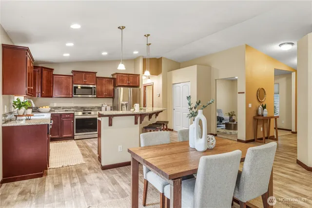 a kitchen with stainless steel appliances granite countertop a stove top oven a sink dishwasher a dining table and chairs