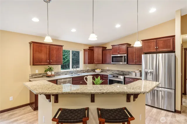 a kitchen with stainless steel appliances granite countertop a sink a stove and a refrigerator