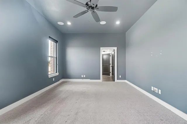 a view of an empty room with a window and a kitchen