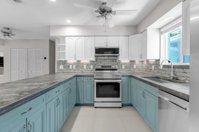 a kitchen with stainless steel appliances granite countertop a refrigerator a sink a stove a microwave and island