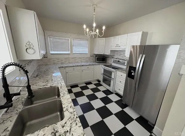 a kitchen with granite countertop stainless steel appliances a sink a refrigerator a counter and cabinets