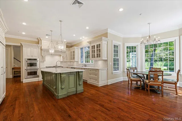 a kitchen with stainless steel appliances granite countertop hardwood floor sink stove dining table and chairs