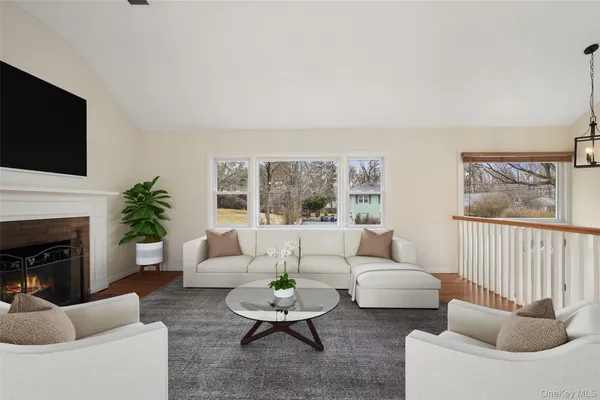 a view of an empty room with wooden floor fireplace and a window