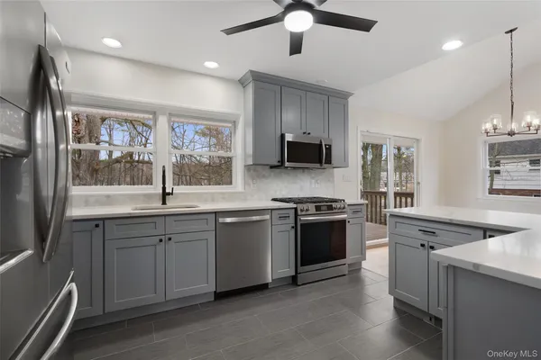 a kitchen with stainless steel appliances granite countertop a stove top oven a sink dishwasher a refrigerator and a dining table with wooden floor