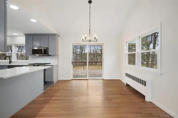 a open kitchen with stainless steel appliances granite countertop a stove a sink dishwasher a refrigerator and white cabinets with wooden floor