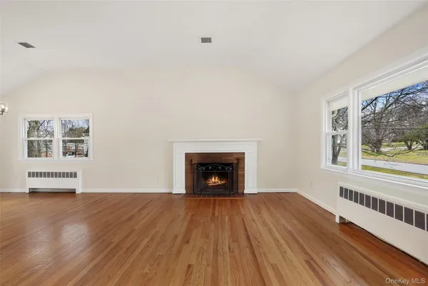 a view of an empty room with a window and wooden floor