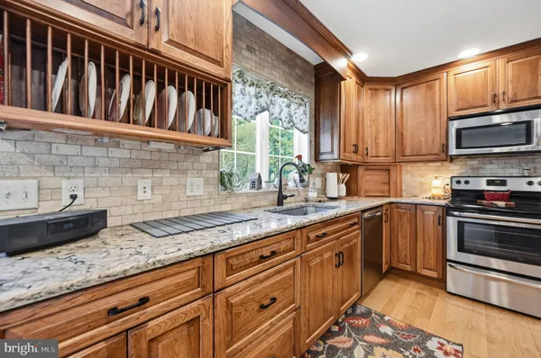 a kitchen with granite countertop a stove a sink and a microwave