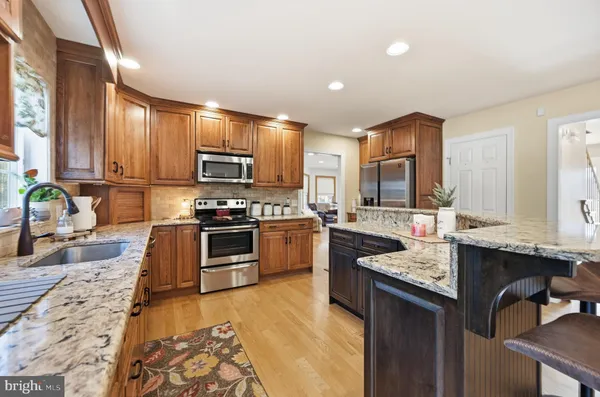 a kitchen with granite countertop a stove top oven a sink dishwasher a dining table and chairs with wooden floor