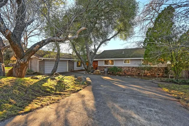 a front view of a house with a yard covered with snow and trees
