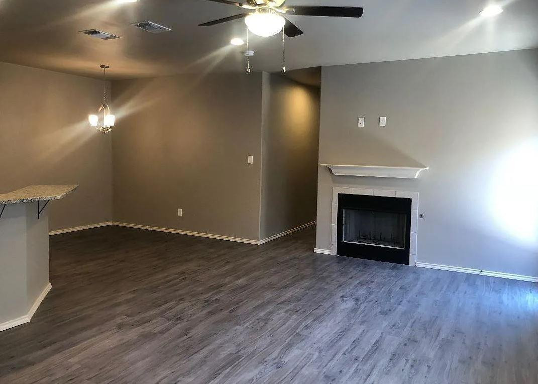 1203 Preston Trail, Unit B Wolfforth, TX 79382 - Photo 2 of 13 an empty room with wooden floor a fireplace