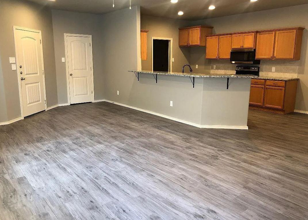 1203 Preston Trail, Unit B Wolfforth, TX 79382 - Photo 3 of 13 a kitchen with stainless steel appliances granite countertop a sink stove and wooden floor