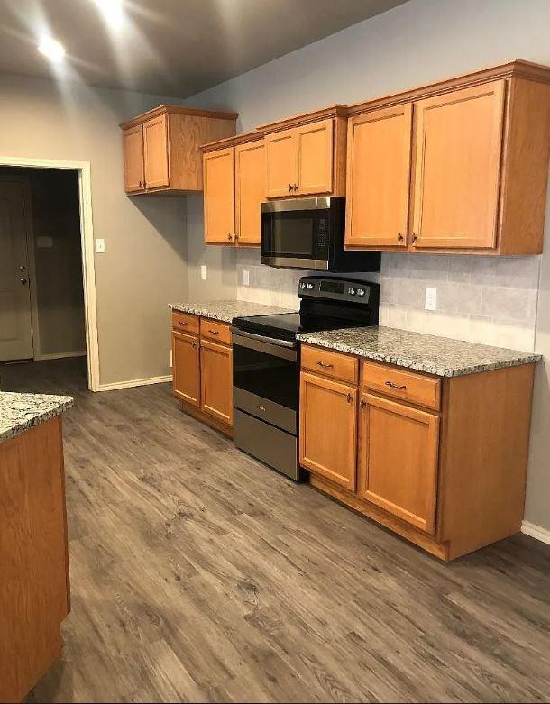 1203 Preston Trail, Unit B Wolfforth, TX 79382 - Photo 5 of 13 a kitchen with stainless steel appliances granite countertop a stove a sink and a microwave