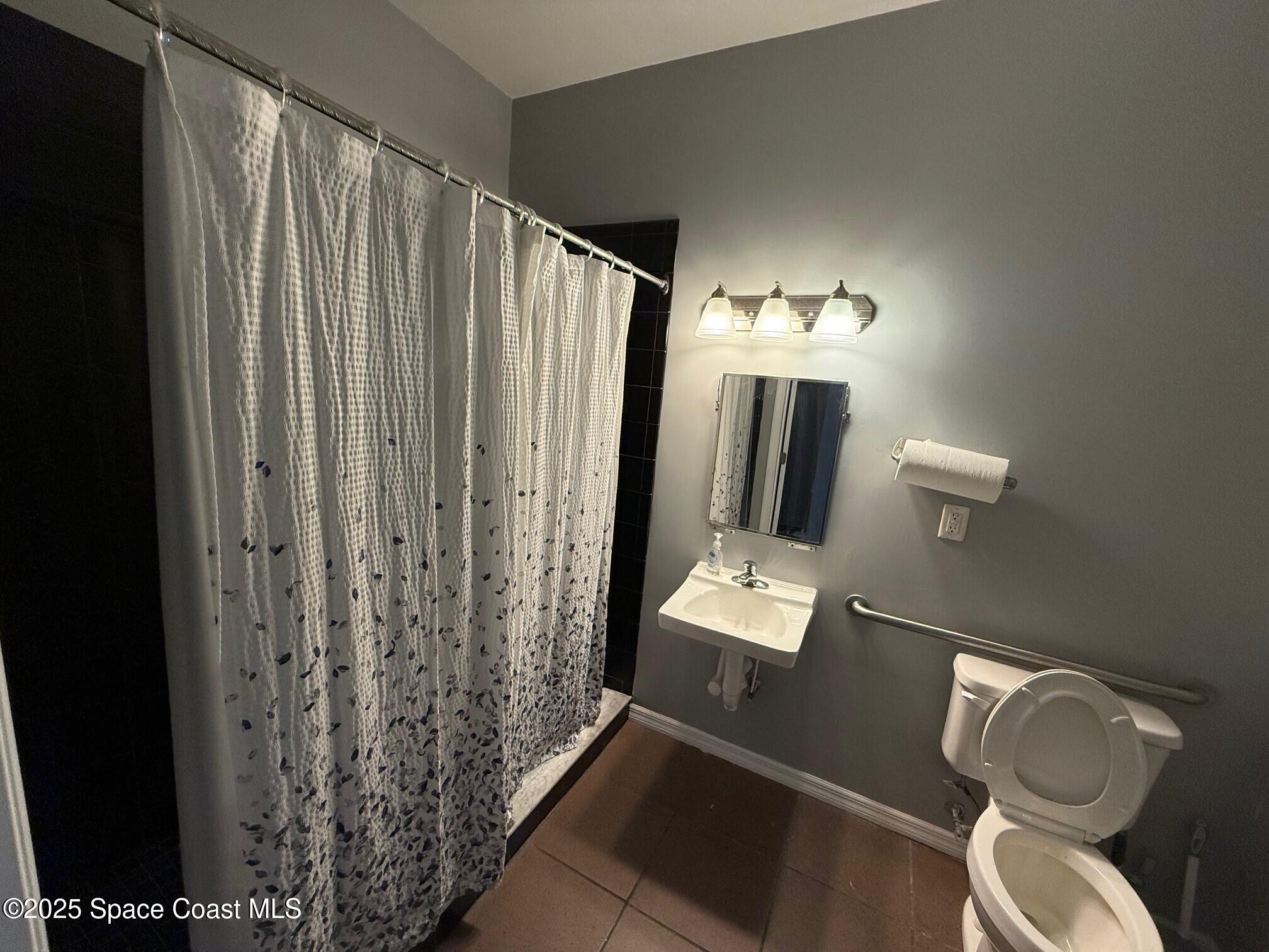 5121 Industry Drive, Unit 103105 Melbourne, FL 32940 - Photo 11 of 13 a bathroom with a toilet a sink and mirror