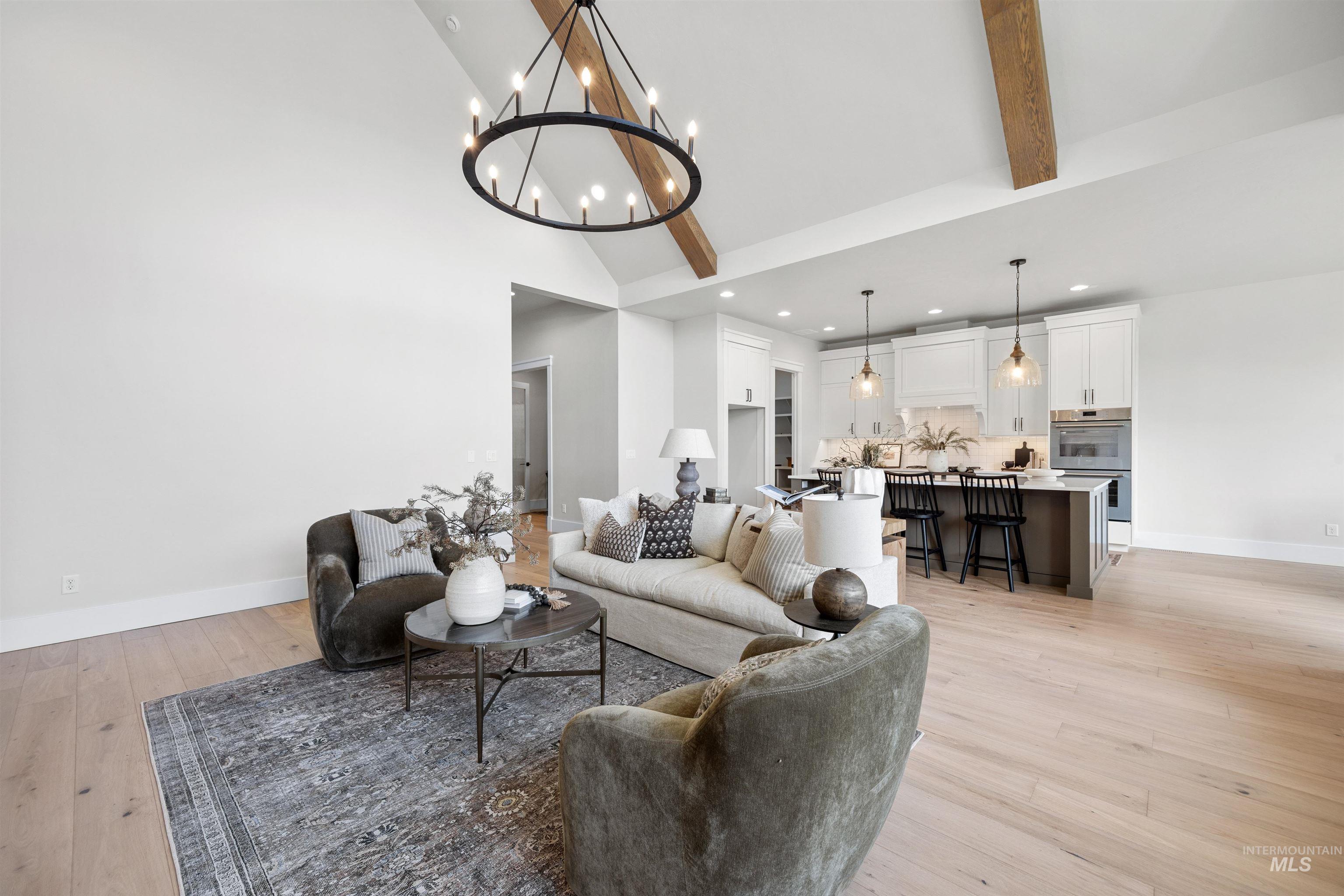 5940 South Pinpoint Way Meridian, ID 83642 - Photo 13 of 40 Vaulted ceilings with exposed wood beams, wood-finish flooring, recessed lighting, kitchen island with seating, and stainless steel appliances