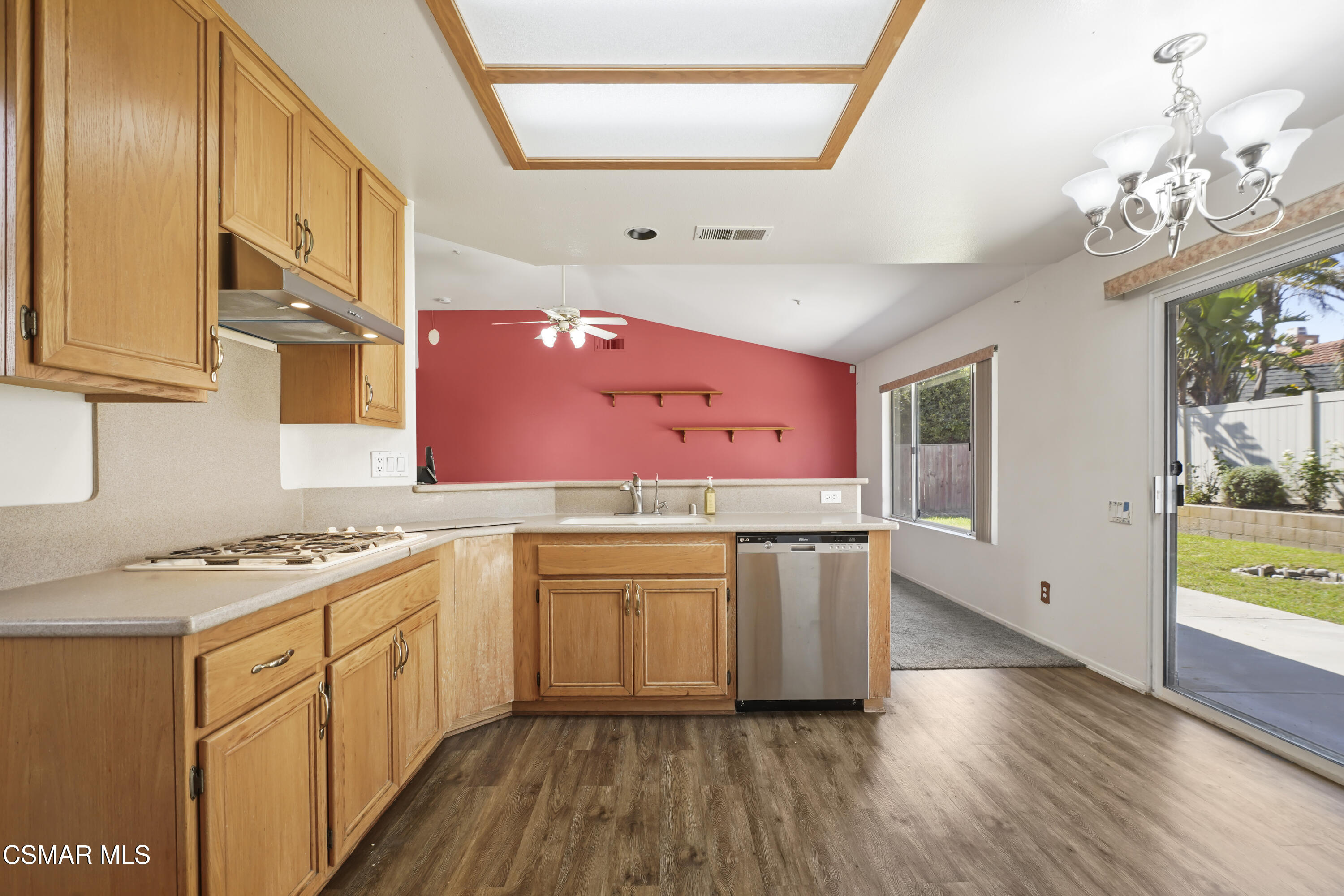 663 Novato Drive Oxnard, CA 93035 - Photo 15 of 40 a kitchen with granite countertop a stove a sink dishwasher and white cabinets with wooden floor