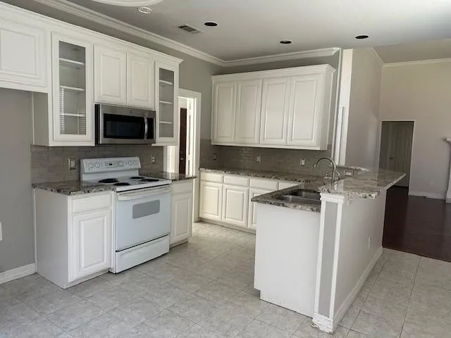 a kitchen with granite countertop a sink stove and microwave