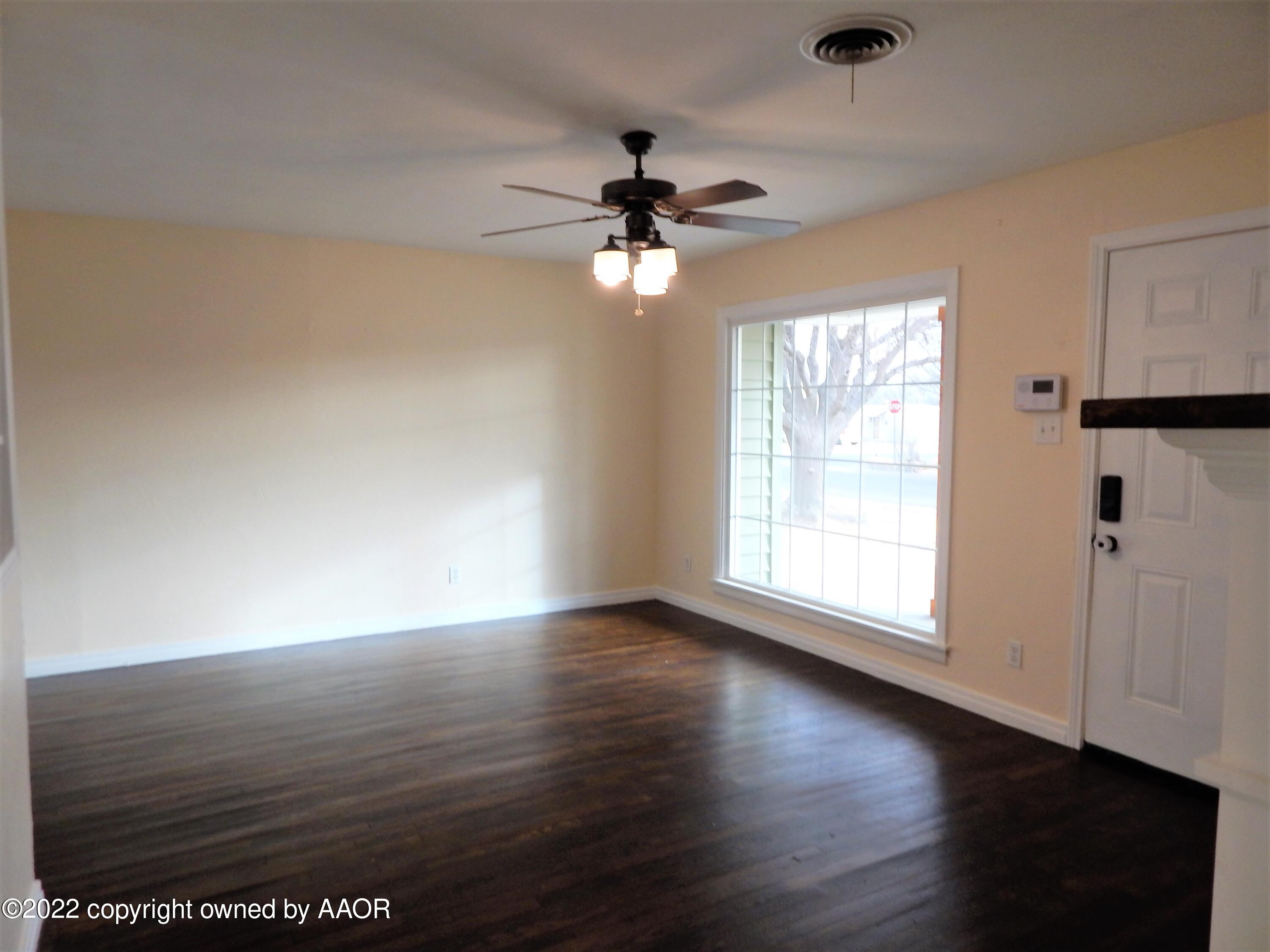 4202 South Lipscomb Street Amarillo, TX 79110 - Photo 7 of 25 an empty room with wooden floor chandelier fan and windows