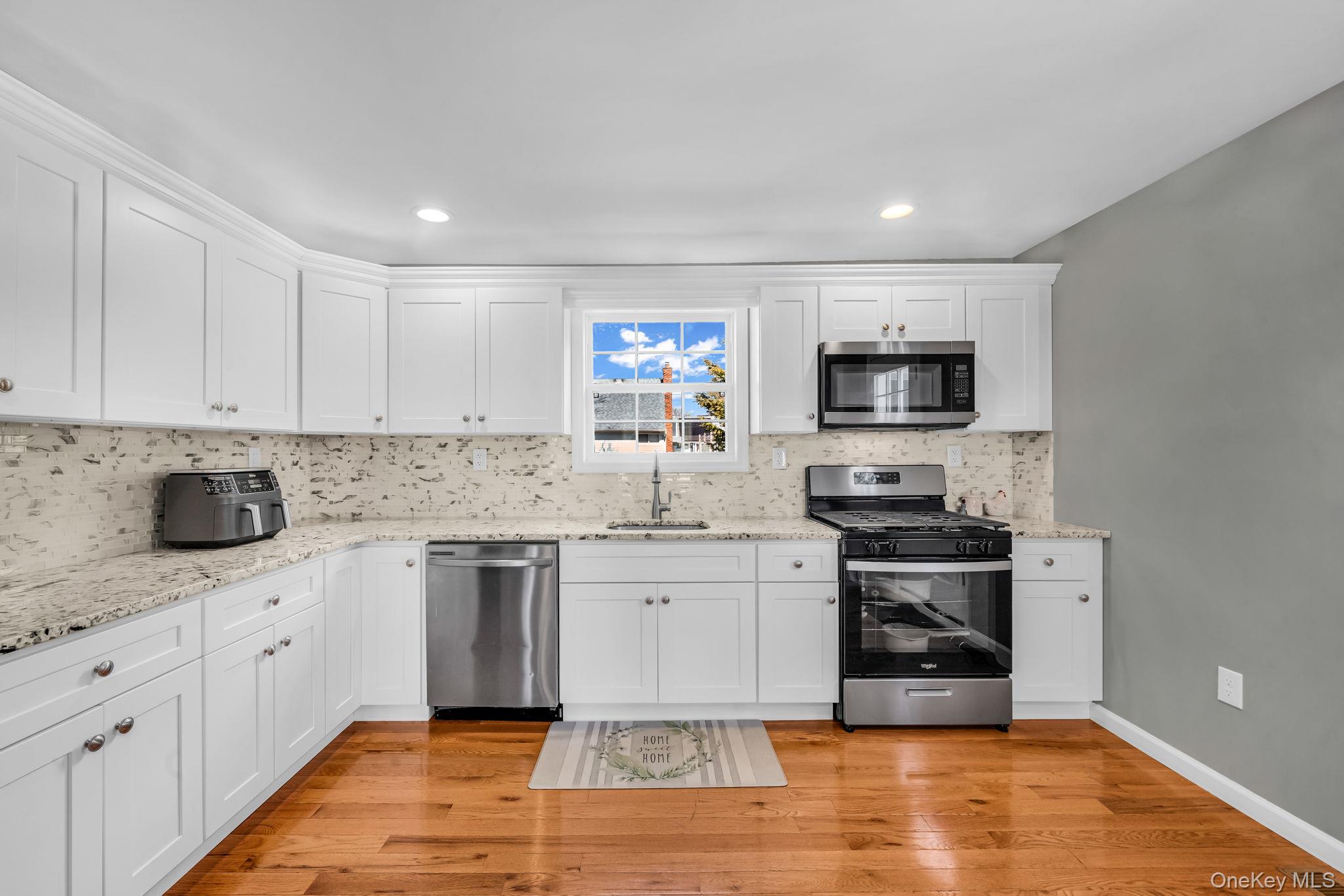 232 30th Street Lindenhurst, NY 11757 - Photo 18 of 46 a large kitchen with stainless steel appliances granite countertop a stove a sink dishwasher and a microwave oven with wooden cabinets