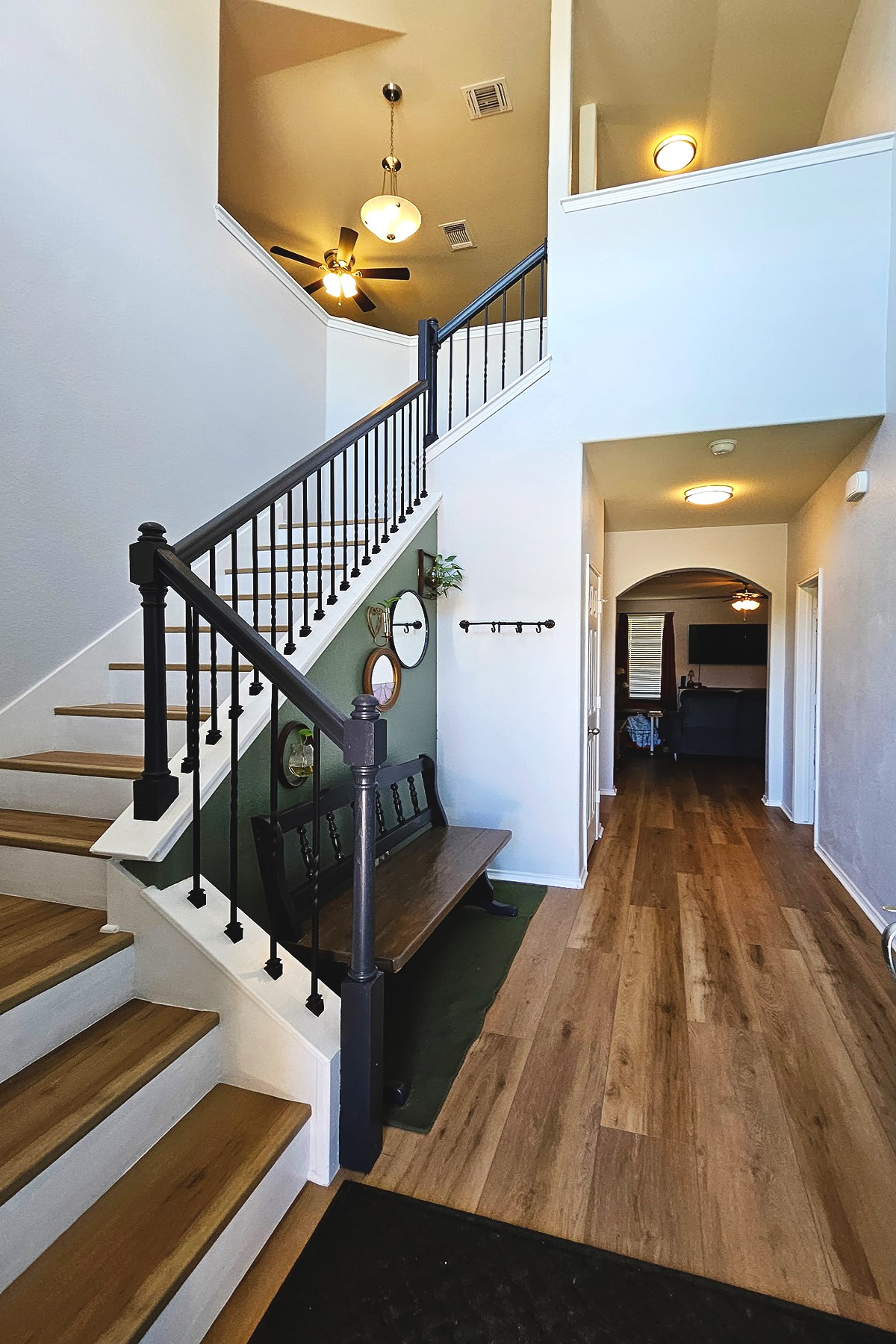 237 Bethann Drive Temple, TX 76502 - Photo 5 of 37 Two-story foyer featuring wood-finish flooring, a contemporary chandelier, a ceiling fan, a staircase with dark balusters, and an arched hallway entry
