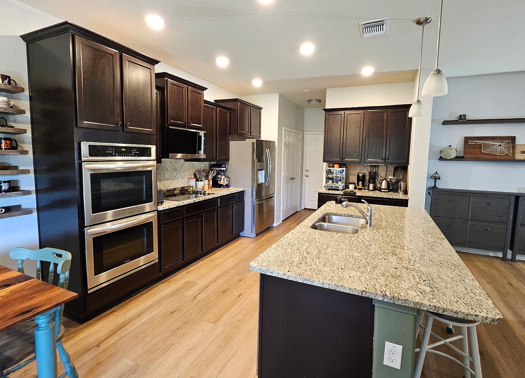 237 Bethann Drive Temple, TX 76502 - Photo 7 of 37 Spacious kitchen featuring an expansive island with a double basin sink, dark wood-finish cabinetry, stainless steel double ovens, and light wood-finish flooring