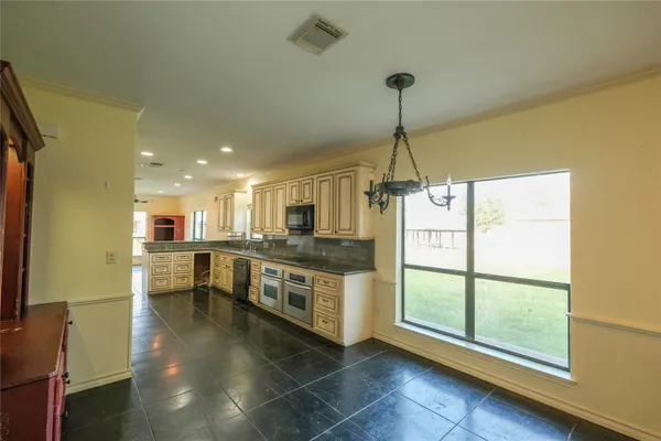 a kitchen with stainless steel appliances granite countertop a refrigerator a sink dishwasher a stove and a dining table with wooden floor