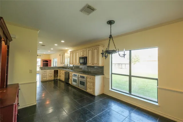 a kitchen with stainless steel appliances granite countertop a refrigerator a sink dishwasher a stove and a dining table with wooden floor