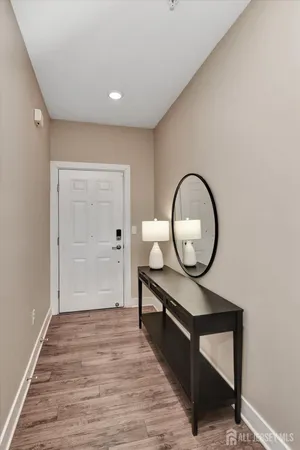 a view of a hallway to a room with wooden floor and white wooden door