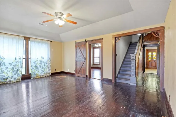 an empty room with wooden floor and windows