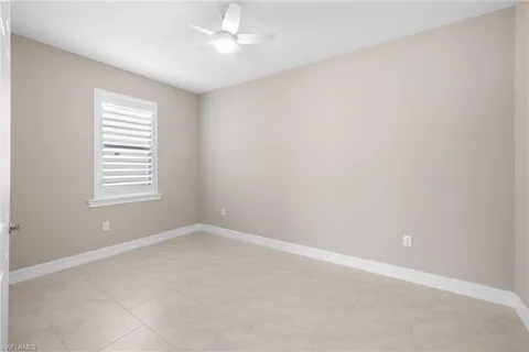 an empty room with a window and ceiling fan