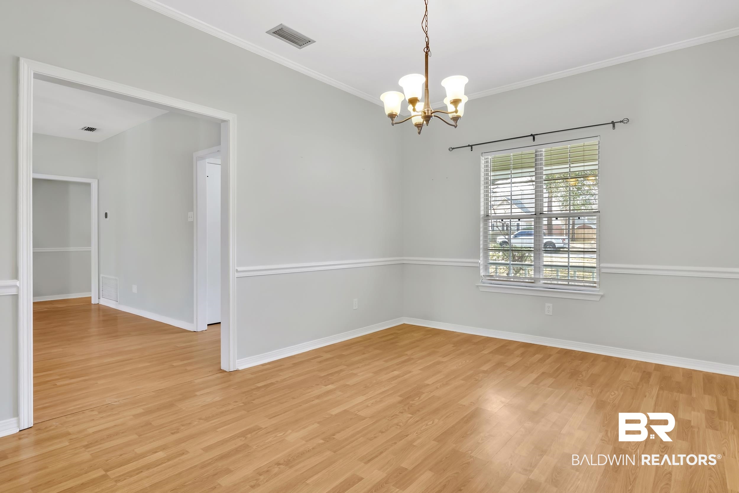 6616 Conde Court Mobile, AL 36695 - Photo 14 of 27 Empty room featuring visible vents, baseboards, crown molding, light wood-type flooring, and a chandelier