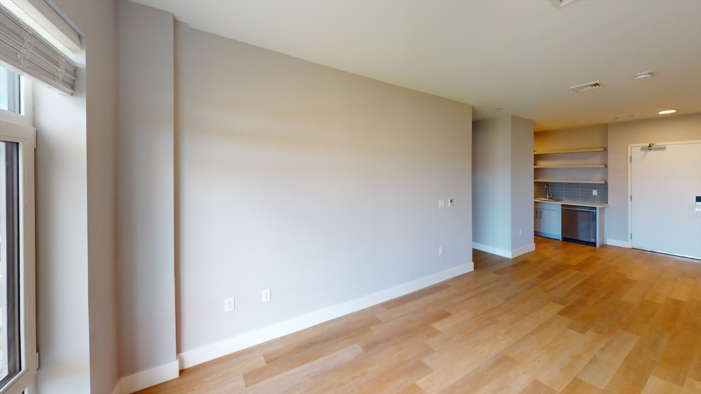 250 Centre Street, Unit 509 Boston, MA 02119 - Photo 3 of 5 a view of empty room with kitchen and window