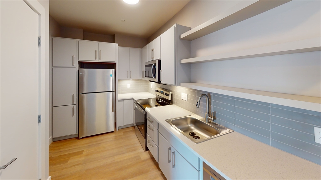 250 Centre Street, Unit 509 Boston, MA 02119 - Photo 4 of 5 a kitchen with a refrigerator a stove top oven and a refrigerator