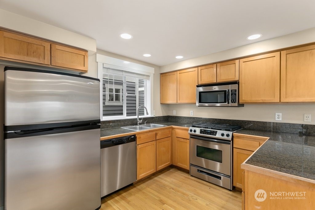 910 Northwest 85th Street, Unit A Seattle, WA 98117 - Photo 7 of 29 a kitchen with stainless steel appliances granite countertop a sink stove and microwave