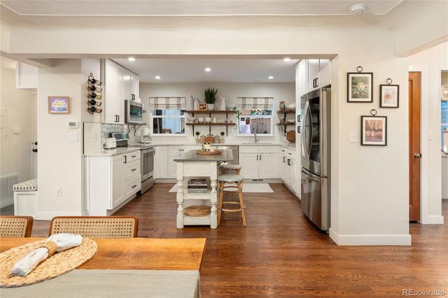 a living room with stainless steel appliances kitchen island granite countertop a refrigerator and microwave