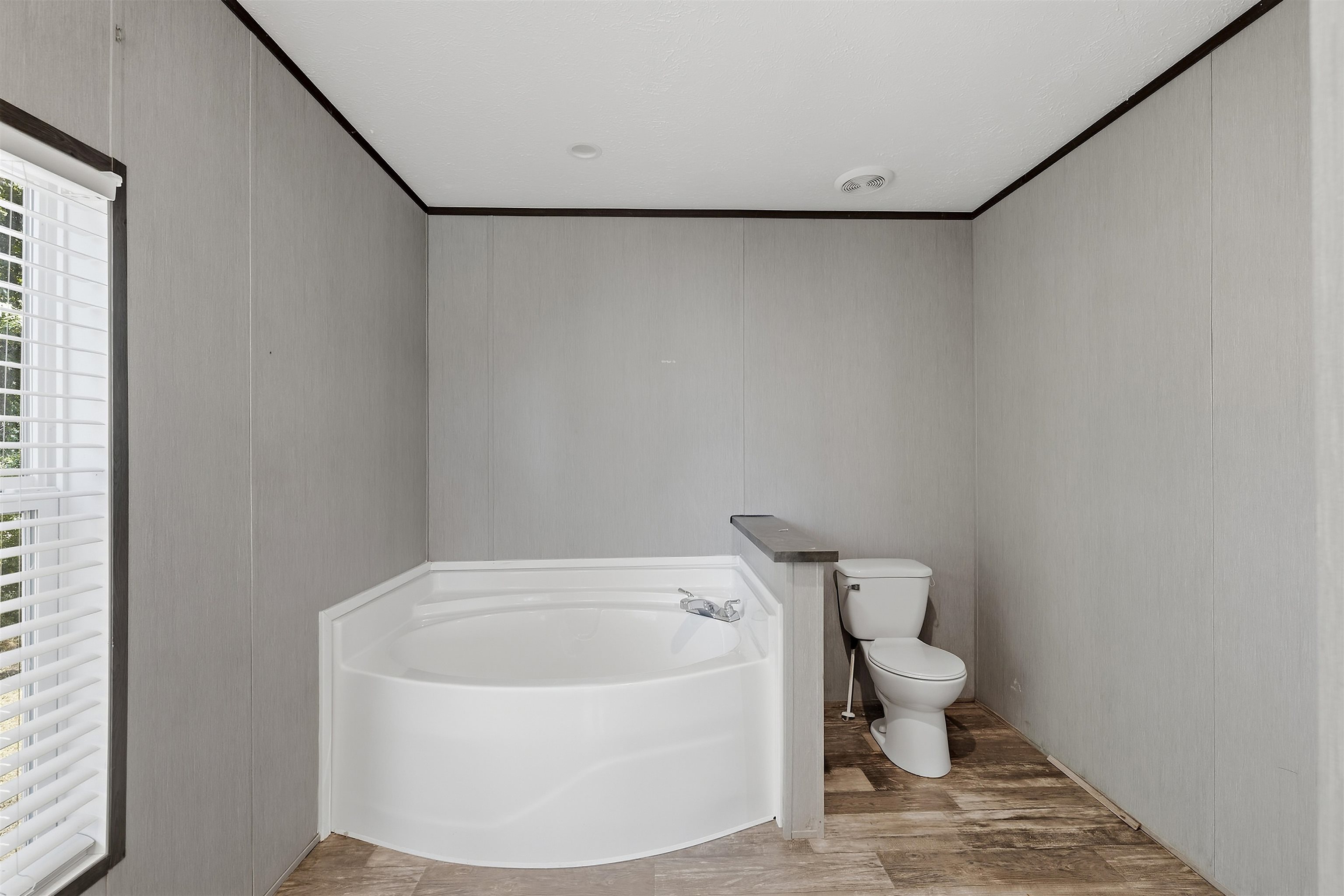 664 Rialto Road Covington, TN 38019 - Photo 11 of 24 Corner soaking tub with deck-mounted faucet and wood-finish flooring