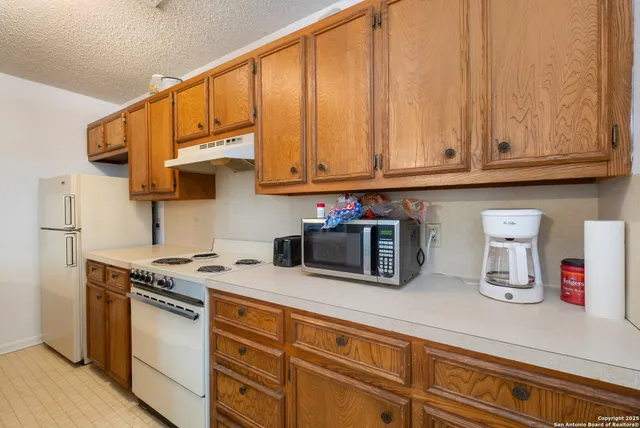 a kitchen with stainless steel appliances granite countertop a refrigerator a stove a sink and white cabinets