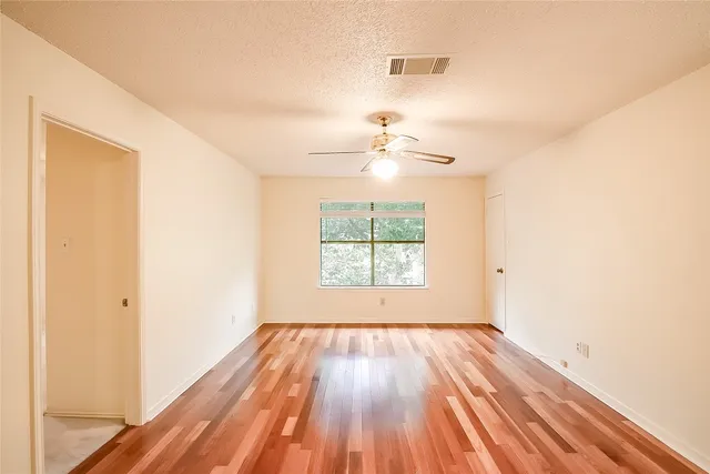 a view of a room with wooden floor a ceiling fan and window